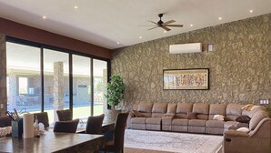A spacious living area with a stone accent wall, a large window, and a ceiling fan. - Rancho Florean - Villa 3 (Montemorelos)