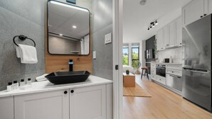A modern kitchen with a black sink, white cabinets, and stainless steel appliances.