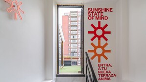 A staircase with black and white tiles leading to a balcony with a view of a red building.