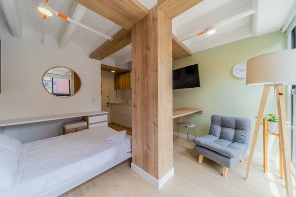 Une chambre à coucher moderne avec un lit, un bureau, une chaise et un téléviseur.