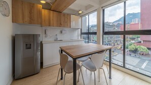 A modern kitchen with wooden cabinets, a stainless steel refrigerator, and a large window offering a city view. - |Ahead| Spacious 3BR @Chapinero with Co-working (Bogotá)