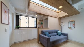 A modern living room with a grey sofa, wooden beams, a skylight, and a view of the outside. - |Ahead| Spacious 3BR @Chapinero with Co-working (Bogotá)