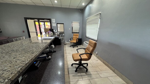 A reception area with a marble counter, office chairs, a bulletin board, and a tiled floor. - spanish trails inn (Lancaster)