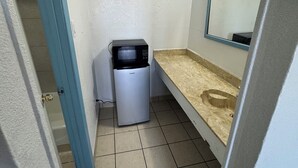 A small bathroom with a toilet, sink, mirror, and a trash bin. - spanish trails inn (Lancaster)