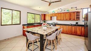 Une cuisine moderne avec des meubles en bois, un îlot en marbre et un ventilateur de plafond.