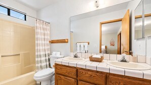 A bathroom with a bathtub, two sinks, a toilet, and a large mirror. - The Great Escape (Big Bear City)