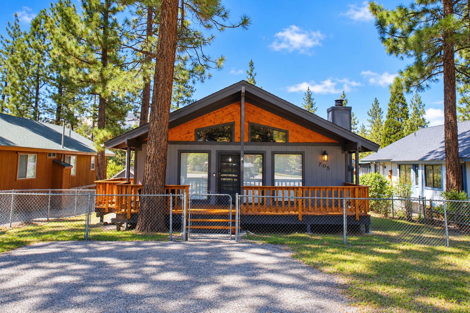 A lodge with a wooden exterior, a porch, and a fenced driveway.