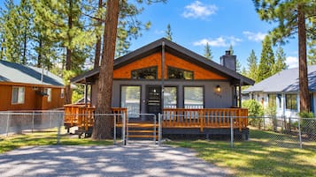 A lodge with a wooden exterior, a porch, and a fenced driveway.