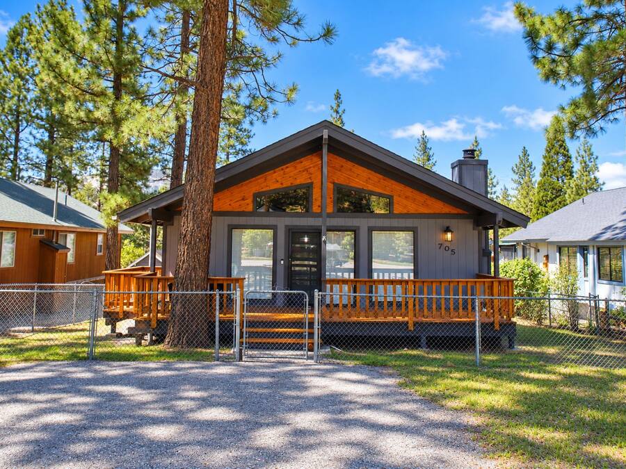 A lodge with a wooden exterior, a porch, and a fenced driveway.