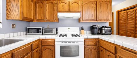 Una cocina con armarios de madera, una estufa blanca, un microondas y una cafetera.