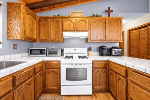 A kitchen with wooden cabinets, a white stove, a microwave, and a coffee maker. - The Great Escape (Big Bear City)