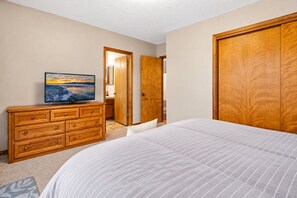 A bedroom with a bed, a wooden dresser, a television, and a wardrobe. - The Great Escape (Big Bear City)