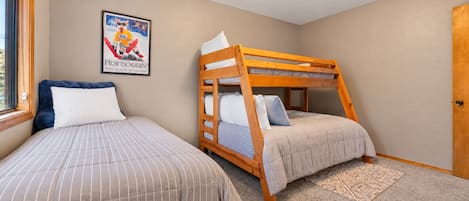 A bedroom with two beds, one with a bunk bed structure and the other a standard bed, both with striped bedding.