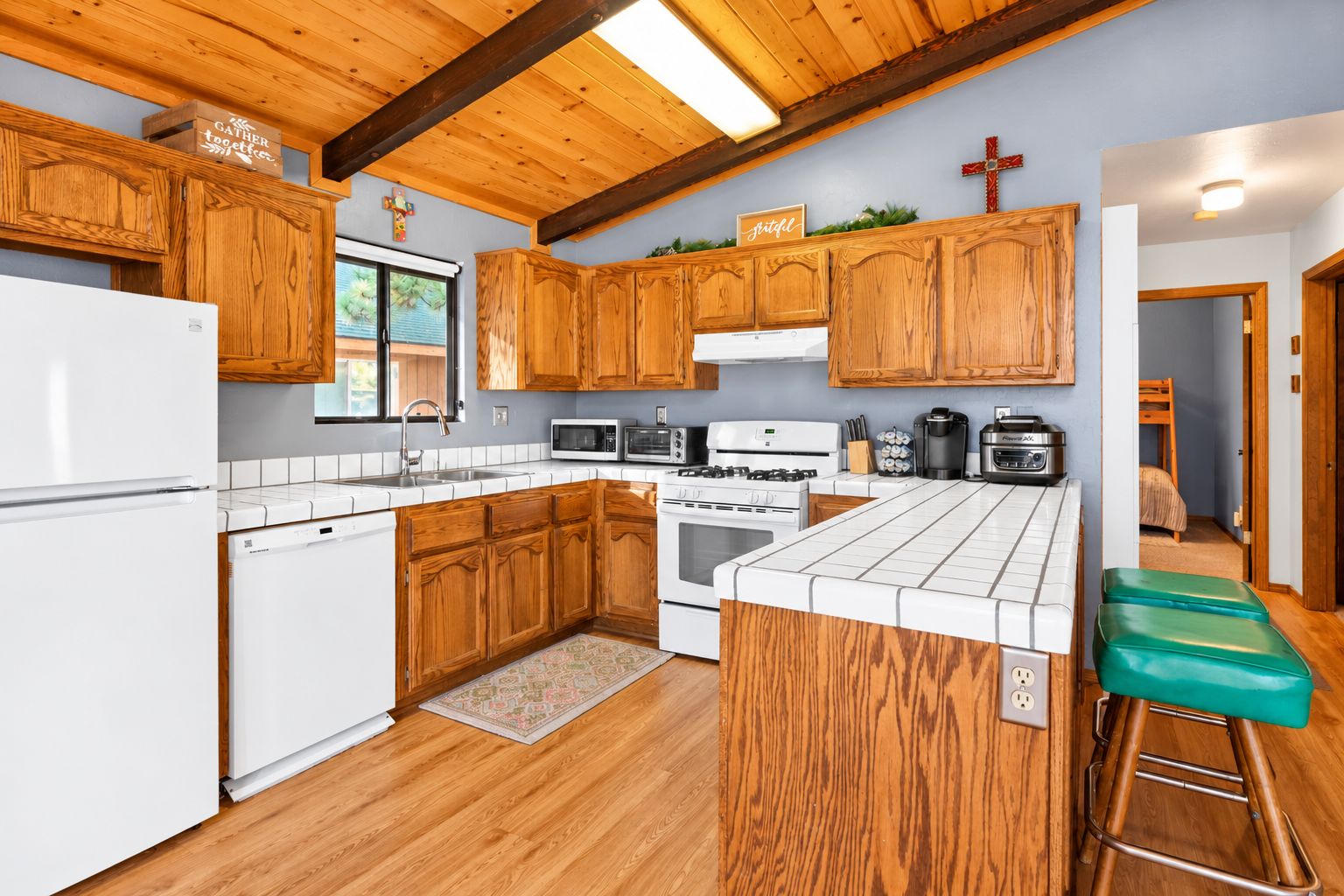 A kitchen with wooden cabinets, a white refrigerator, a microwave, a stove, and a coffee maker.