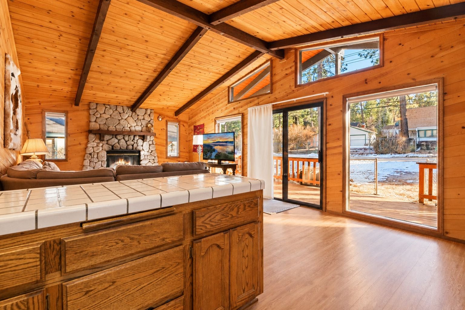 A wooden interior with a stone fireplace, a sofa, and a television.