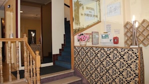 A hotel reception area with a staircase, a reception desk, and a wall-mounted sign. - Hotel Les Portes D'Or (Nancy)