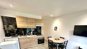 Eine moderne Küche mit Holzausstattung, einem eingebauten Ofen und einem Essbereich mit rundem Tisch und Stühlen.
