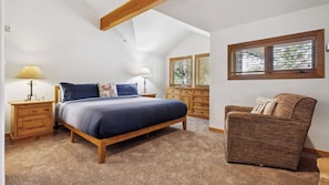 A bedroom with a bed, nightstands, a dresser, a chair, and a window with blinds.