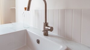 A modern bathroom with a white sink and a sleek, curved faucet. - The (Courdemanche)