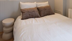 A bedroom with a bed, two wall-mounted lights, a toilet, and a mirror. - The (Courdemanche)