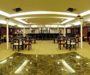 A spacious hotel lobby with a marble floor, multiple seating areas, and a bar in the center. - Movenpick MS Royal Lily Nile Cruise (Luxor)