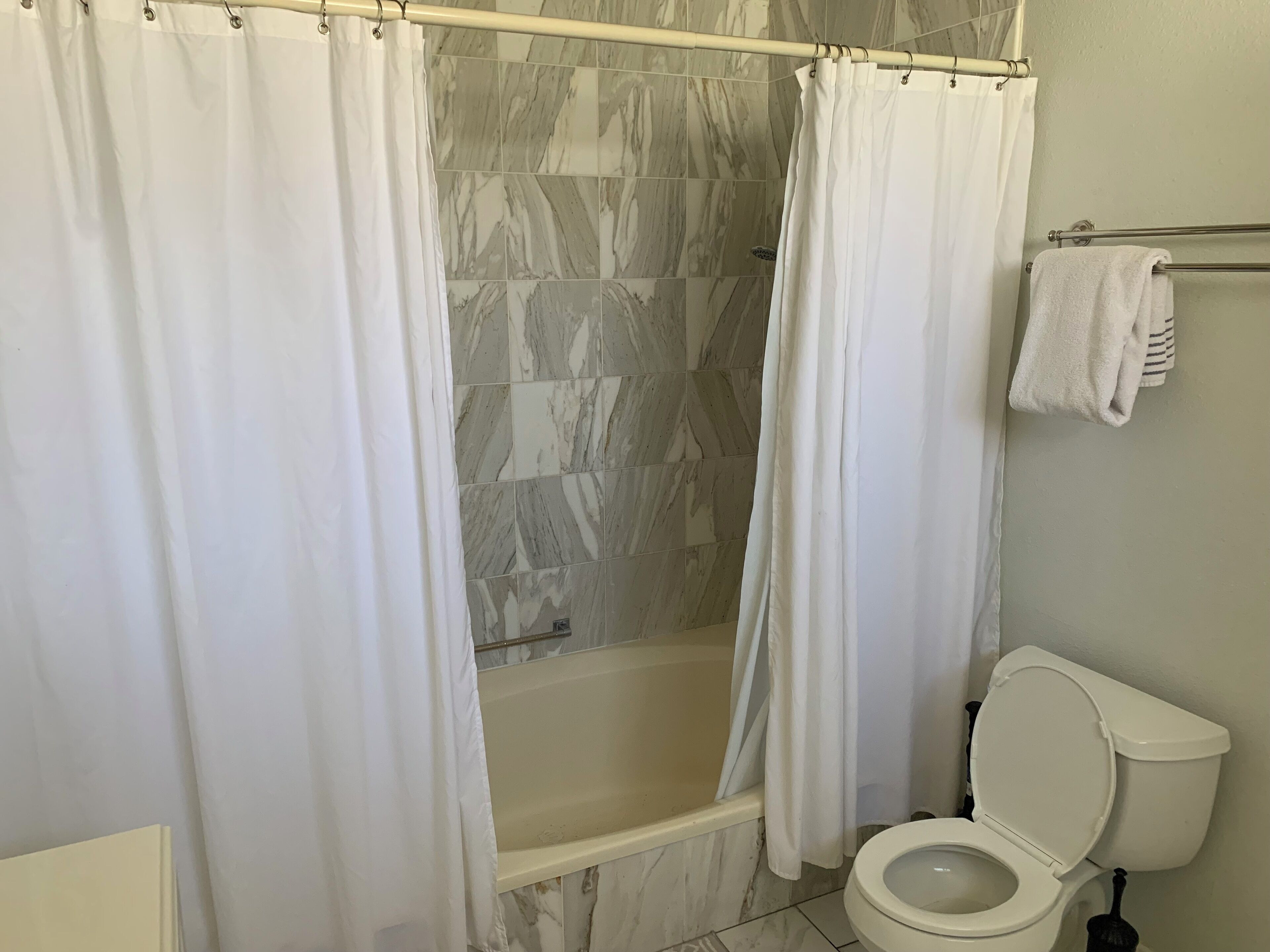 Een badkamer met een douche, bad en toilet.