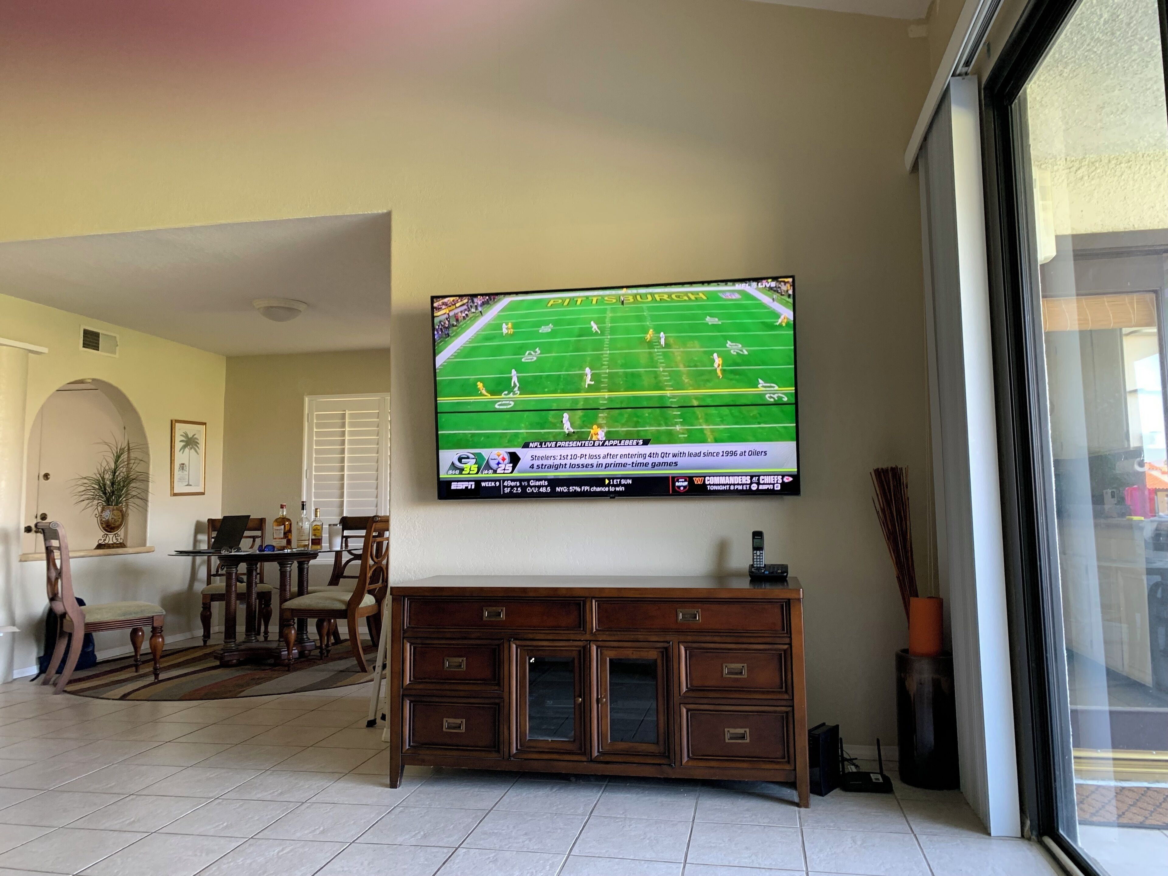 Una sala de estar con un televisor de pantalla plana montado en la pared mostrando un partido de la NFL.