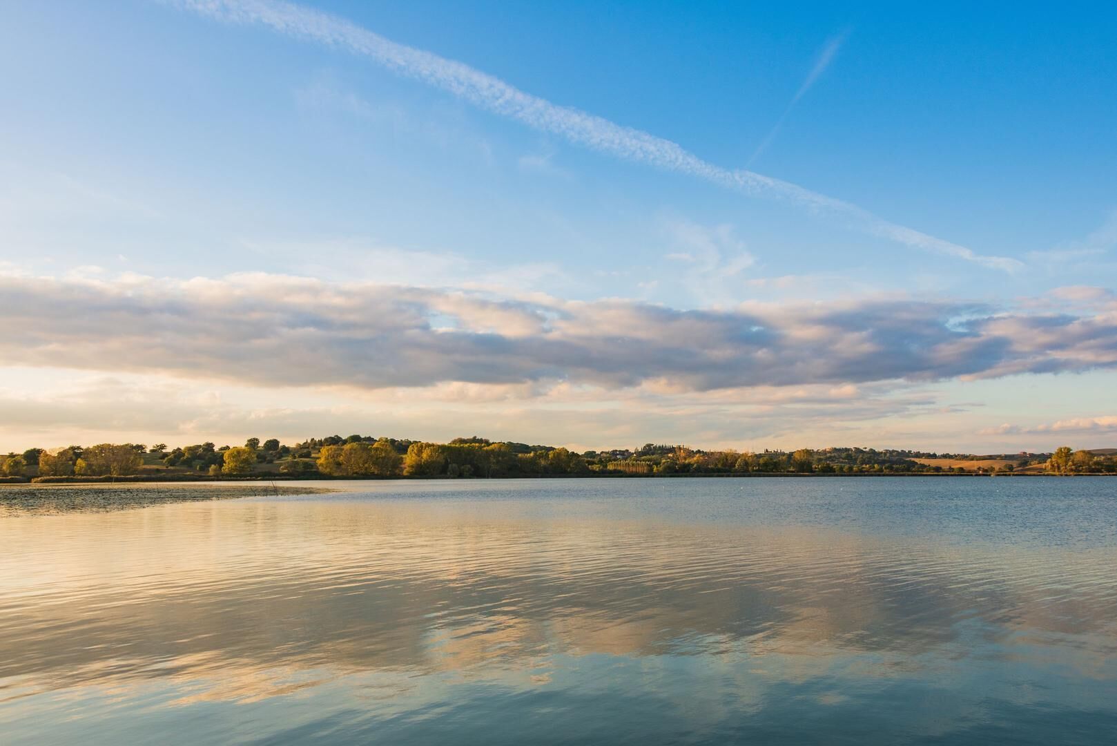 A calm lake with a clear sky and distant trees.