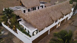 Un edificio con tetti in paglia e facciata bianca, circondato da palme.