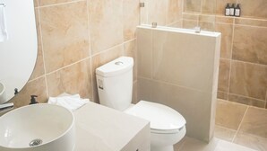 Et moderne badeværelse med beige fliser, en hvid vask og et toilet.