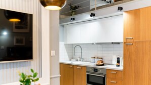 A modern kitchen with white cabinets, a stainless steel sink, and a built-in oven.