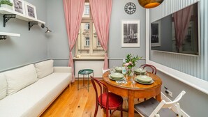 A cozy dining area with a round table set for four, a sofa, and a window with curtains.