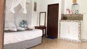 A bedroom with a bed, a bedside table, a mirror, and a decorative fireplace. - Taman Ayu Homestay Munduk Mitra RedDoorz (Bali)