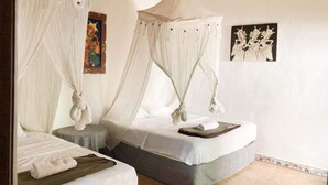 A room with two beds, each with a canopy, and artwork on the walls. - Taman Ayu Homestay Munduk Mitra RedDoorz (Bali)