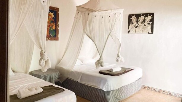 A room with two beds, each with a canopy, and artwork on the walls. - Taman Ayu Homestay Munduk Mitra RedDoorz (Bali)