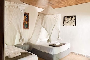 A room with two beds, each with a canopy, and artwork on the walls.