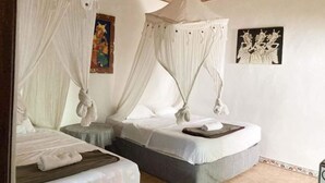 A room with two beds, each with a canopy, and artwork on the walls. - Taman Ayu Homestay Munduk Mitra RedDoorz (Bali)