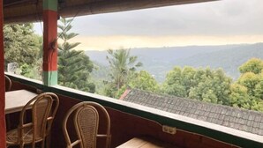 A covered outdoor seating area with wicker chairs and a table, overlooking a mountainous landscape. - Taman Ayu Homestay Munduk Mitra RedDoorz (Bali)