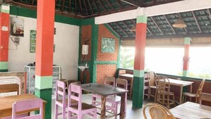 A dining area with tables and chairs, a brick wall, and a ceiling with a green and red pattern. - Taman Ayu Homestay Munduk Mitra RedDoorz (Bali)