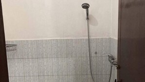 A shower with a handheld showerhead and a wall-mounted faucet. - Taman Ayu Homestay Munduk Mitra RedDoorz (Bali)