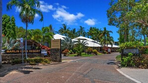 A resort entrance with a sign for Marlin Cove Resort, palm trees, and a clear sky. - Wallaby Hideaway (Trinity Beach)