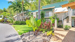 A tropical resort with a paved walkway, lush greenery, and a multi-story building with balconies. - Wallaby Hideaway (Trinity Beach)