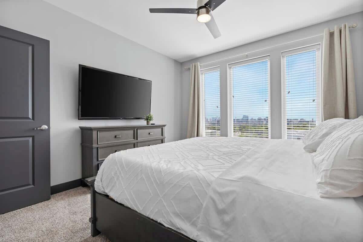 Un dormitorio con una cama, televisión, cómoda y ventilador de techo.