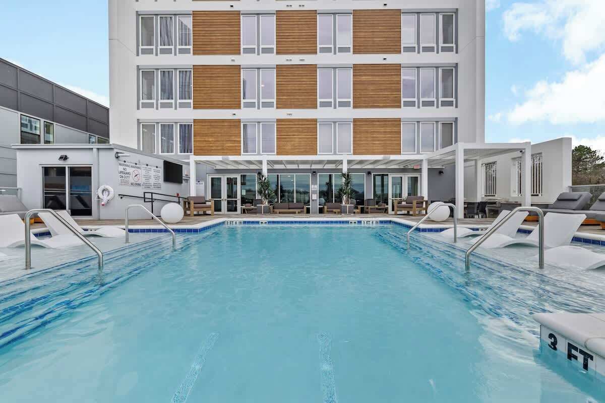 Un hôtel moderne doté d’une piscine, d’un espace extérieur aménagé et d’un bâtiment à plusieurs étages avec de grandes fenêtres.