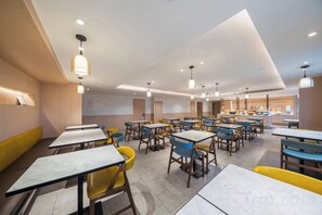 A modern restaurant interior with multiple tables and chairs, a counter area, and pendant lighting. - HanTing Premium Hotel (Beijing Jinsong Subway Station) (Beijing)