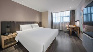A modern hotel room with a large bed, bedside table, lamp, and a view of the city through large windows. - HanTing Premium Hotel (Beijing Jinsong Subway Station) (Beijing)