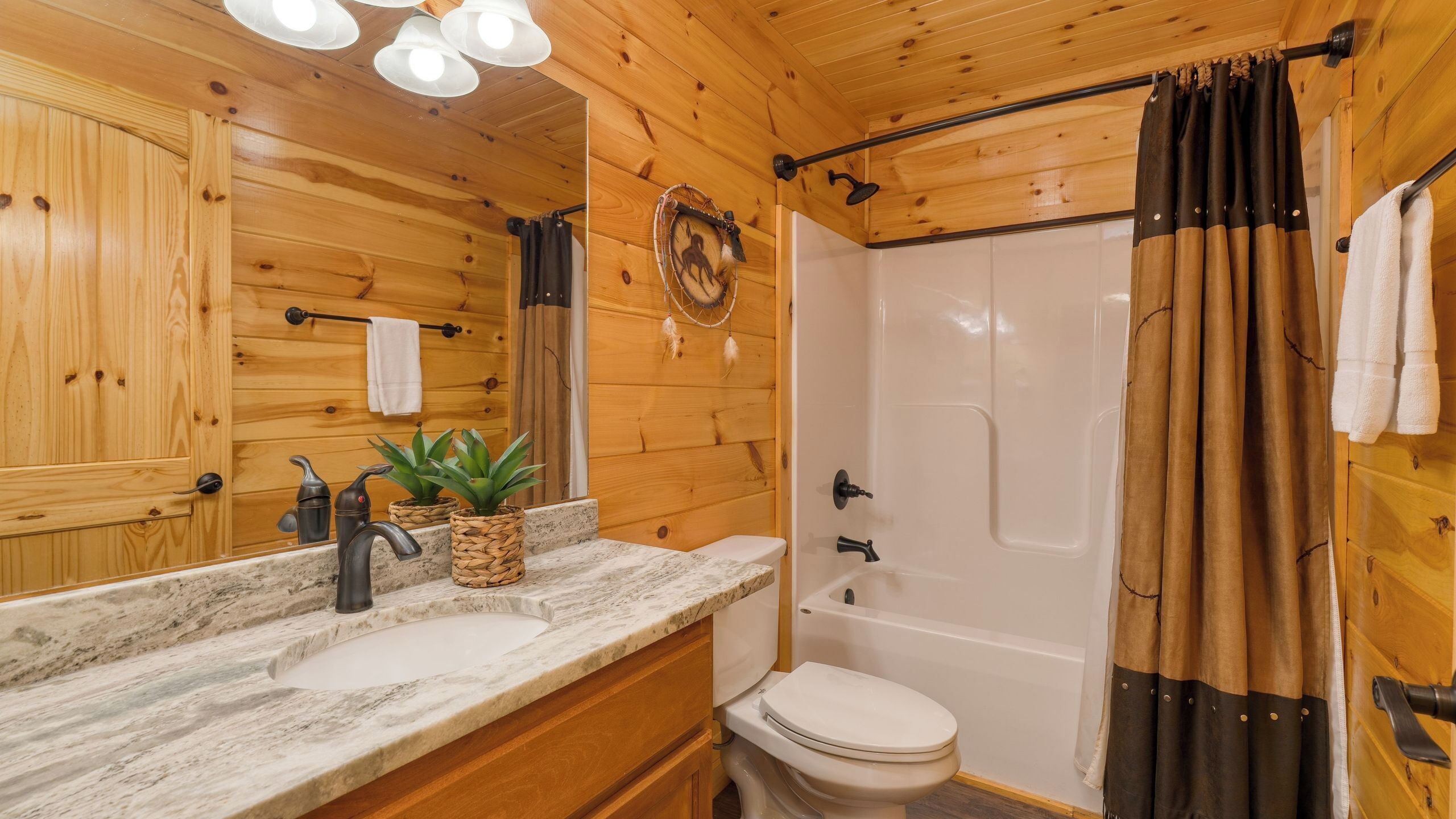 A wooden cabin bathroom with a sink, toilet, and shower.