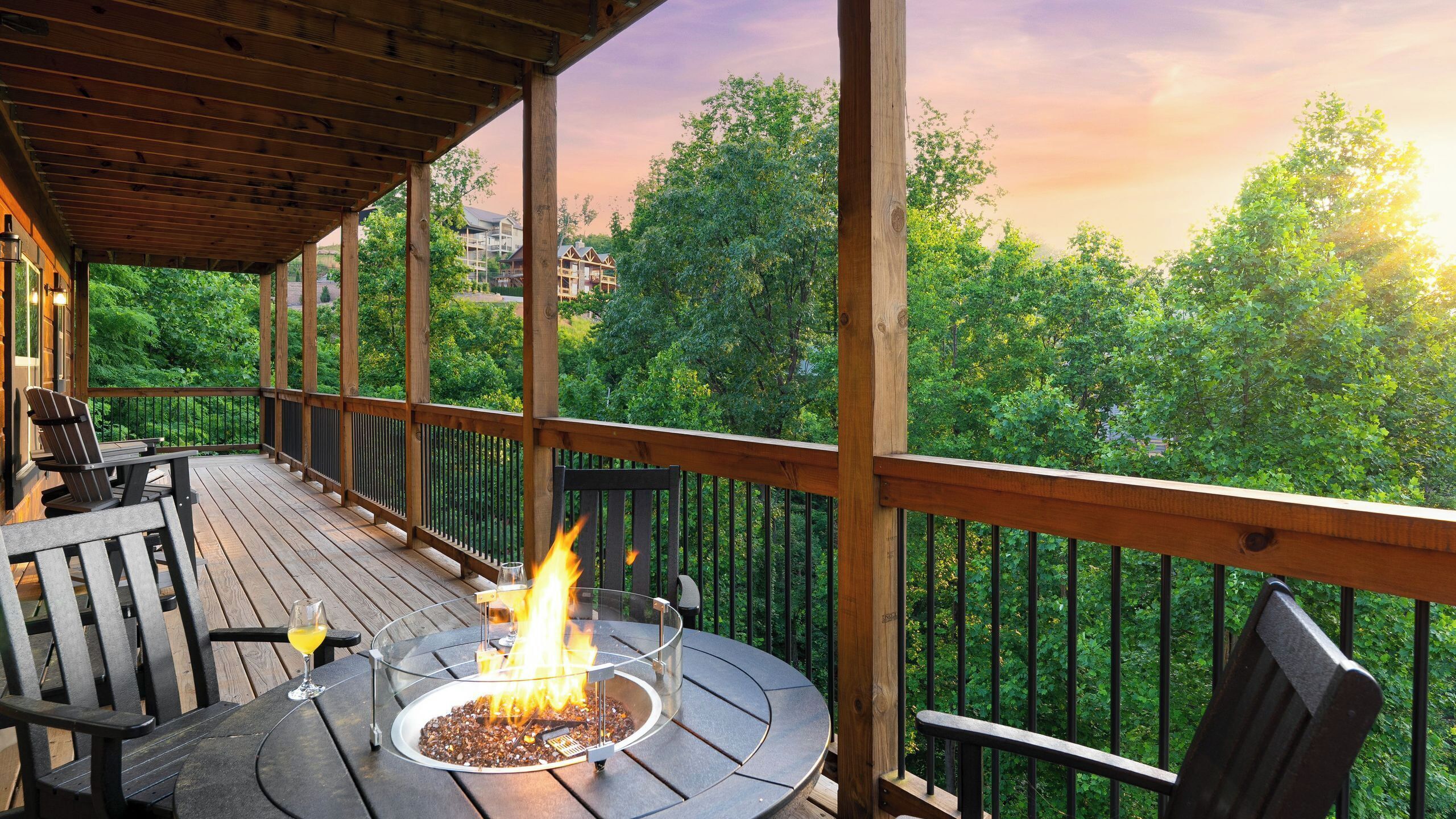 Terraza de madera con un hogar, asientos al aire libre y vistas a un bosque.