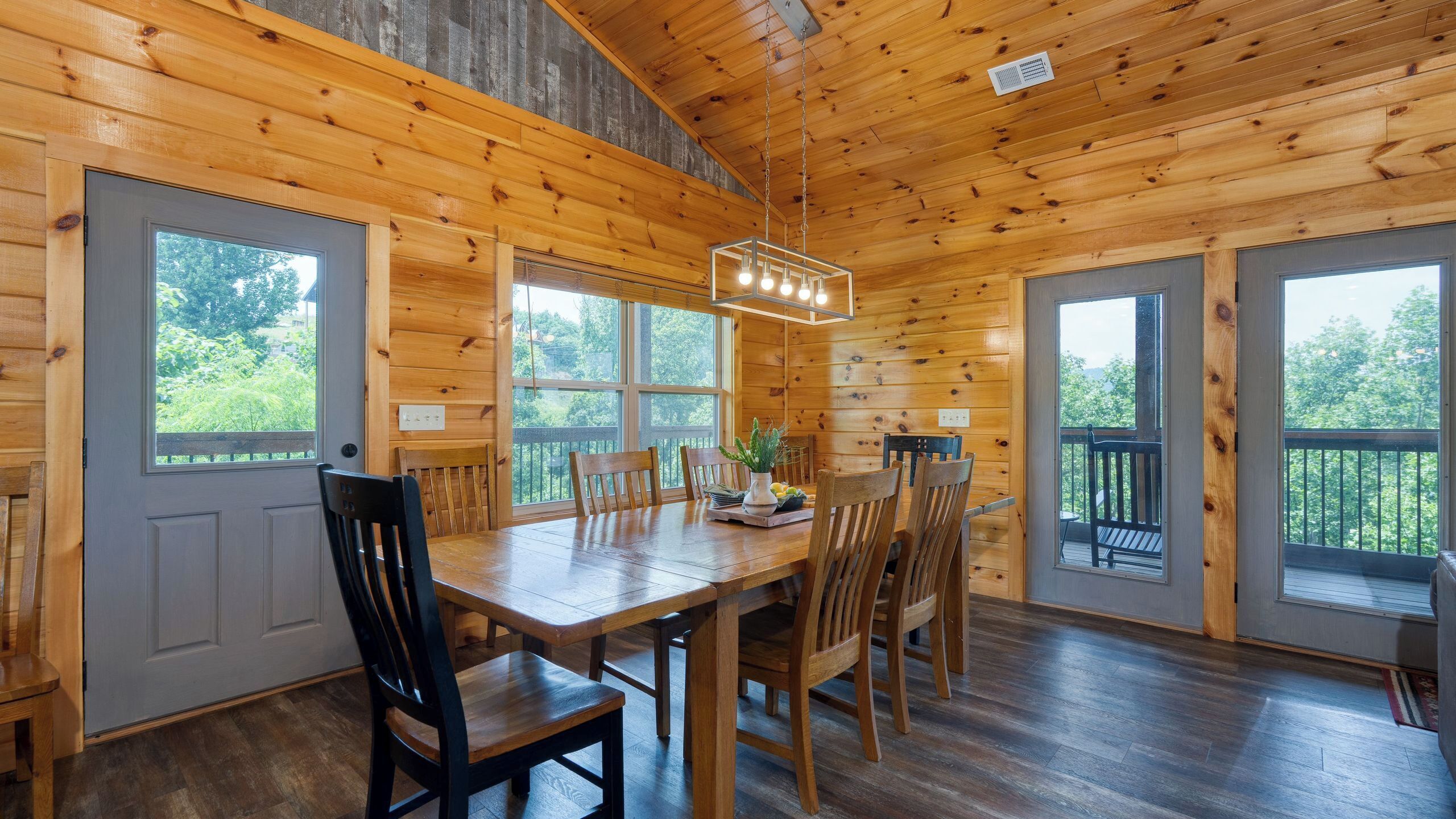 Een houten cabin met een eettafel, stoelen en een kroonluchter.