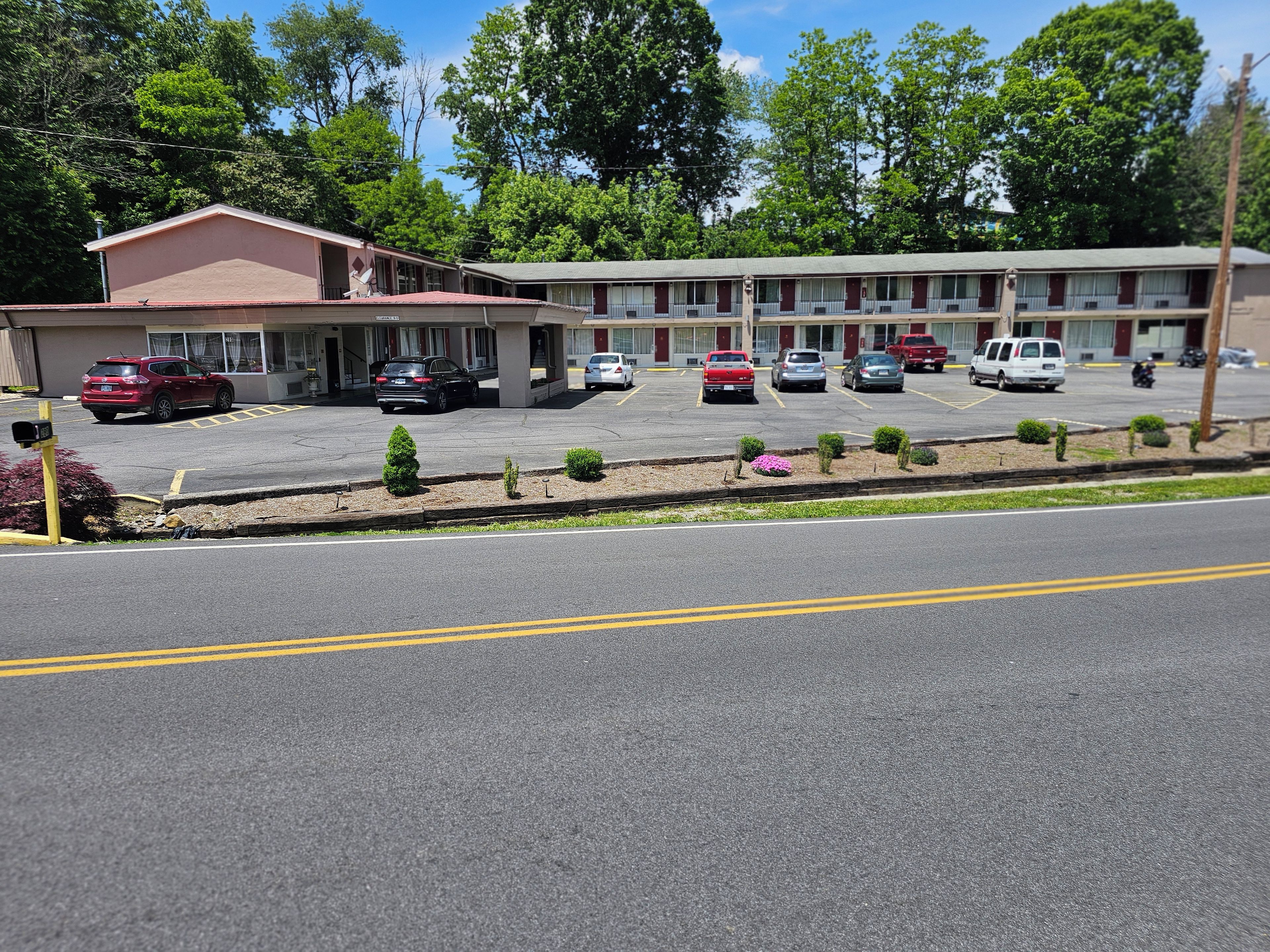 Un motel doté de nombreuses places de stationnement, d’un petit jardin agrémenté d’arbustes et d’un bâtiment à toit plat.